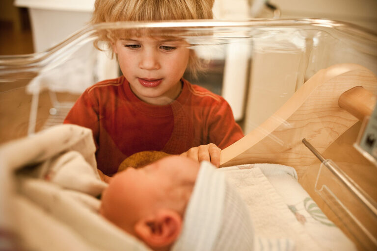 Boy looking at newborn baby brother in hospital