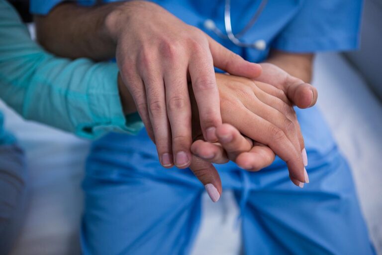 Mid-section of doctor consoling patient in hospital