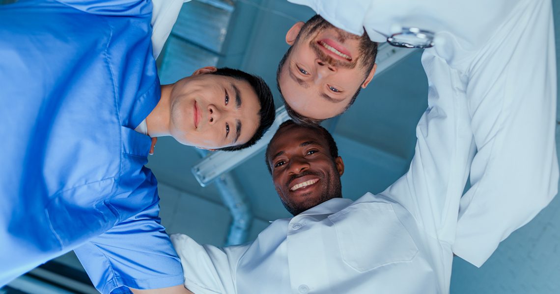 bottom view of multiracial group of doctors standing in circle in clinic