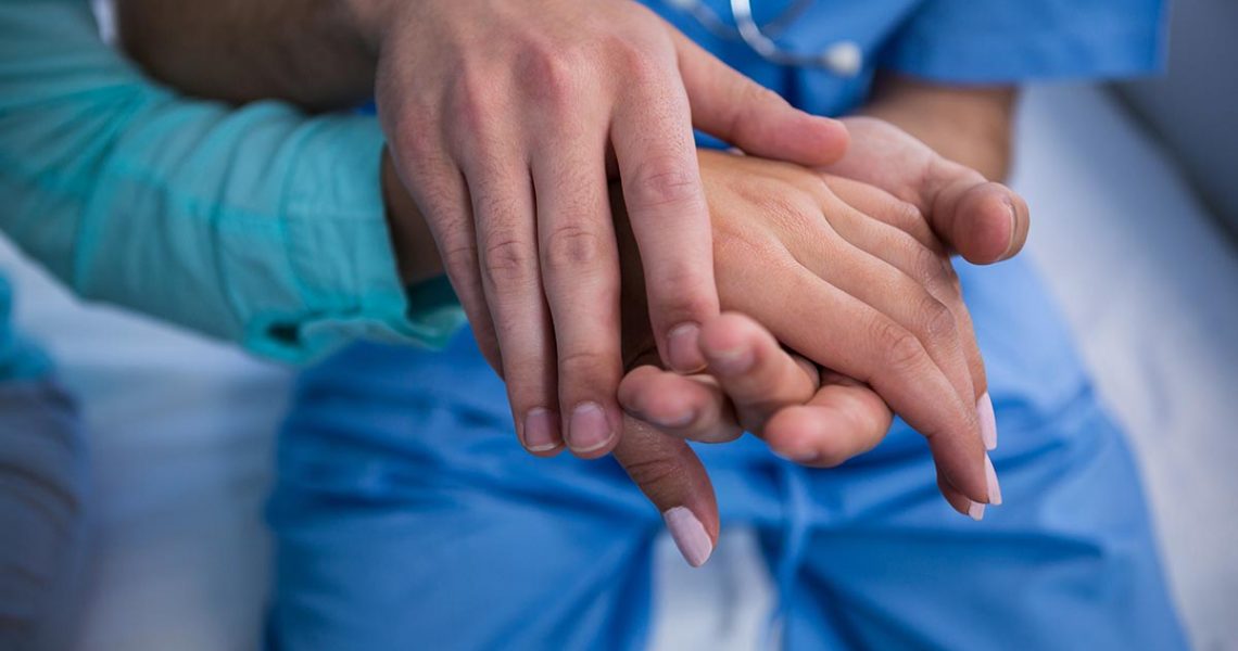 Mid-section of doctor consoling patient in hospital