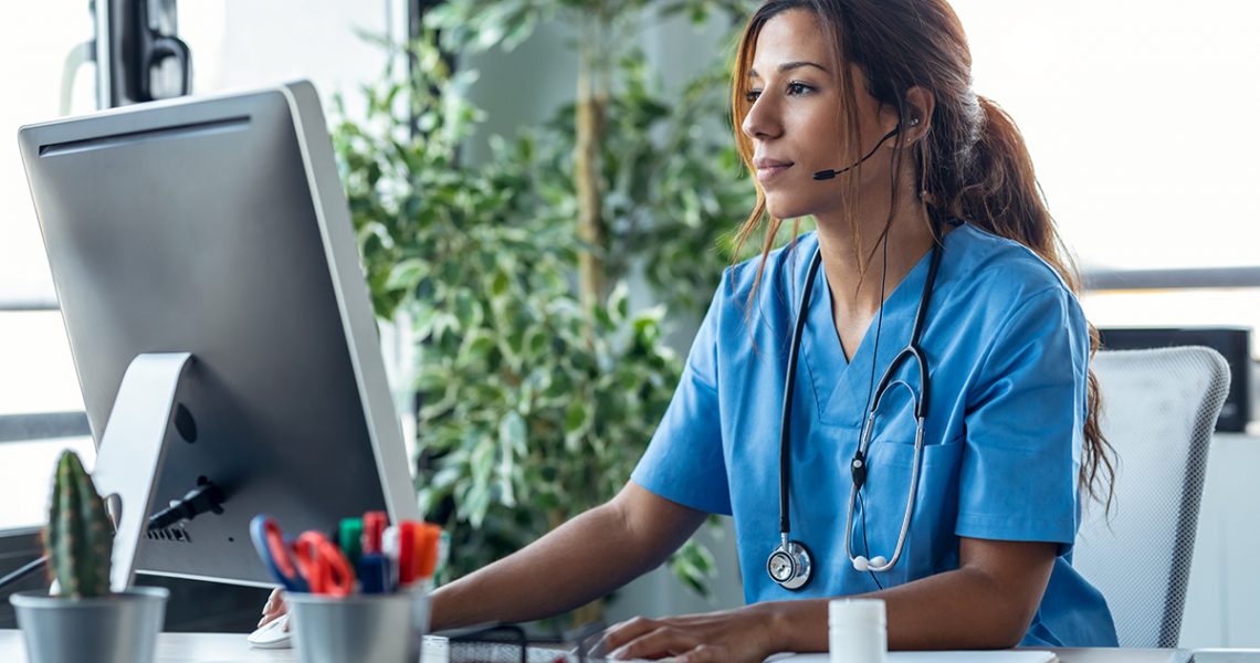 Shot of female doctor talking with earphone while explaining medical treatment to patient through a video call with computer in the consultation.