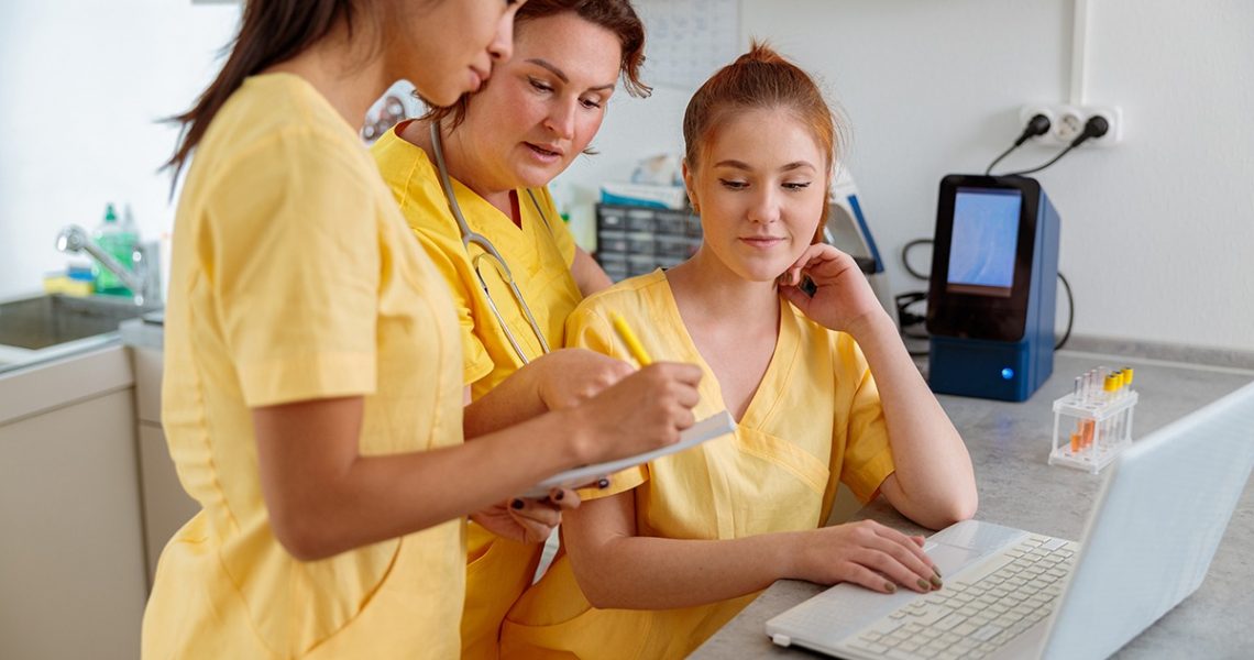 Closeup of friendly team nurses in working uniform discussing working moments in interior of modern clinic